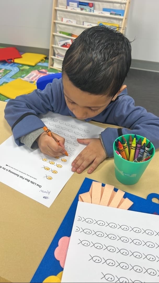 Child working on a drawing activity at the table