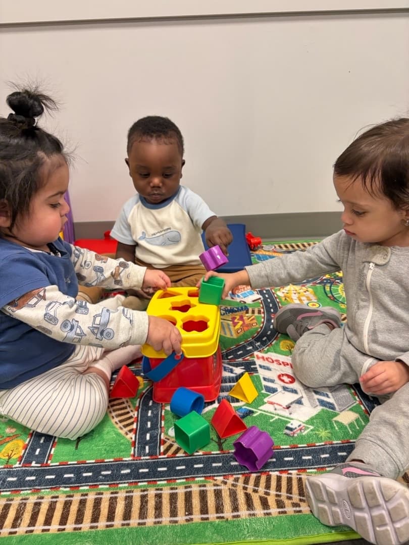 Toddler-age children playing together during a table activity